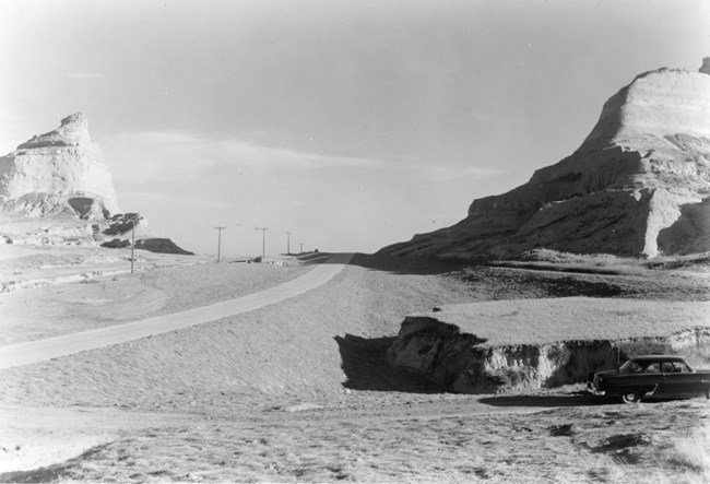 State Highway 86 A paved road passes between sandstone bluffs.