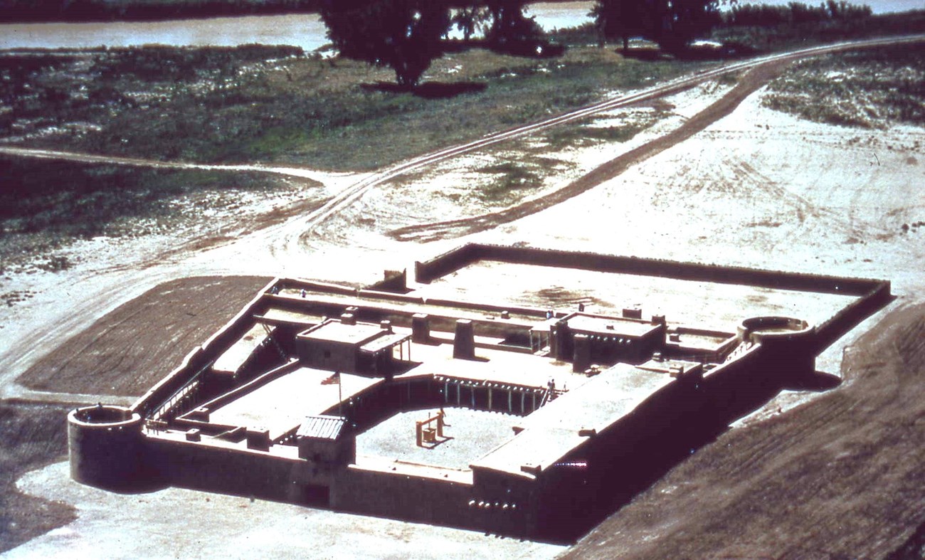an aerial show of a large adobe fort surrounded by fields dusted with snow