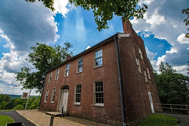 19780331_650798708459816_8408299634625842224_o_FONE_weather_2023 A brick building (Mount Washington Tavern) with brick patio under a blue sky