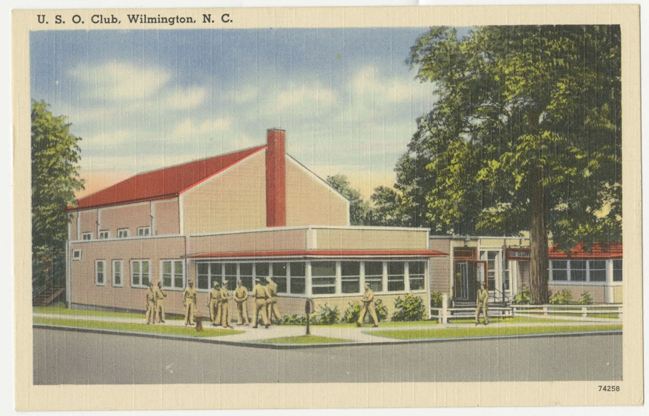 Postcard of the U.S.O. Club showing the side profile of the building and a tree next to the building