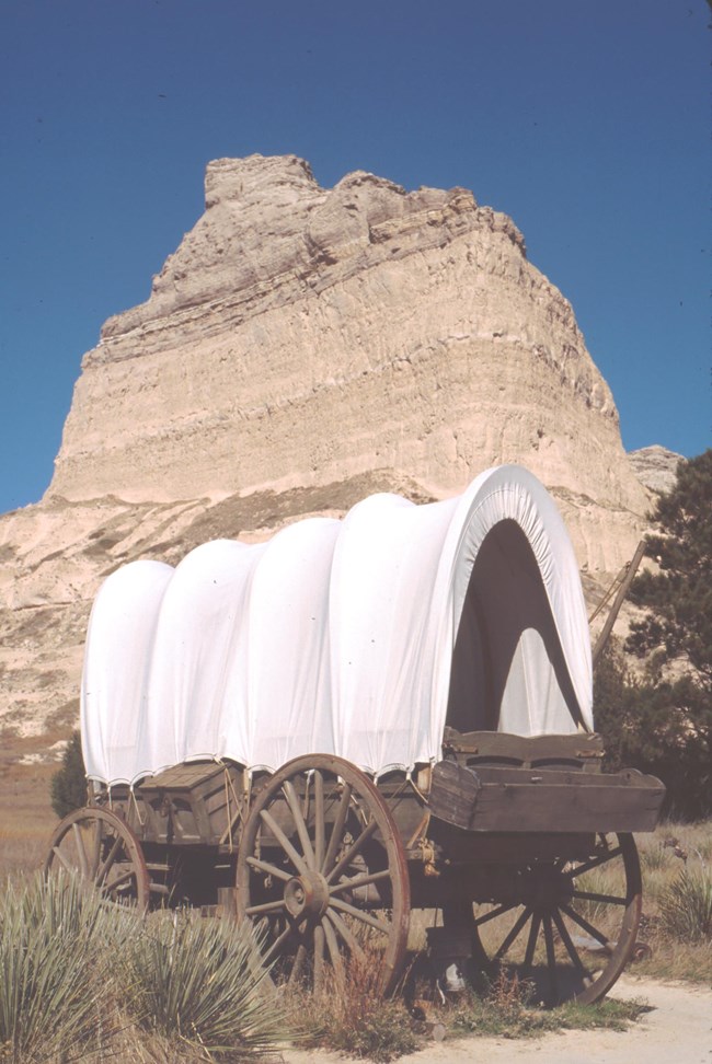 A replica Murphy wagon in front of a distinct sandstone formation.