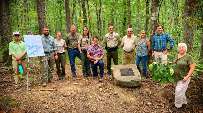 Group of people in forest with sign and plaque