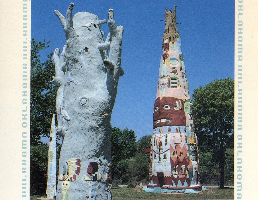 Two poles: Left- gray tree trunk, animals carved in it, Indians with feathers. Right distance multicolored cone shape.