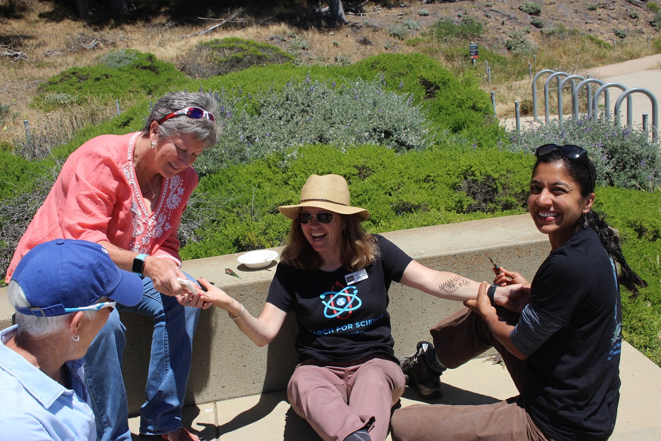 The author drawing a henna tattoo on the arm of one of her Parks Conservancy co-workers at Land's End.