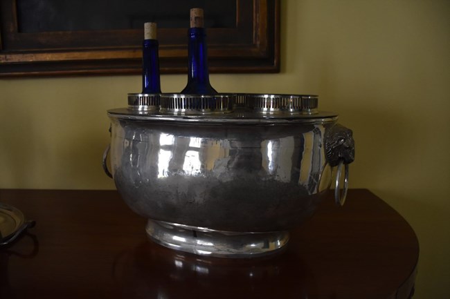 Silver wine cooler with with two blue wine bottles inserted in the cooler.