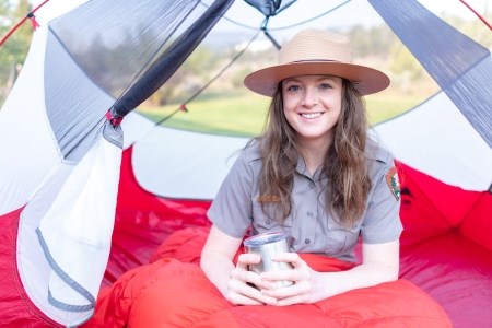 A park ranger in uniform sitting in a tent