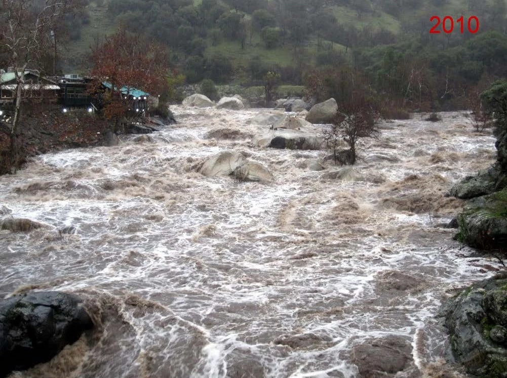 December 19, 2010 - High-flow event on the Kaweah River from large amount of rain over short time period. View from bridge of murky river water rushing over most large boulders, and flowing at high level, bank to bank in river channel.