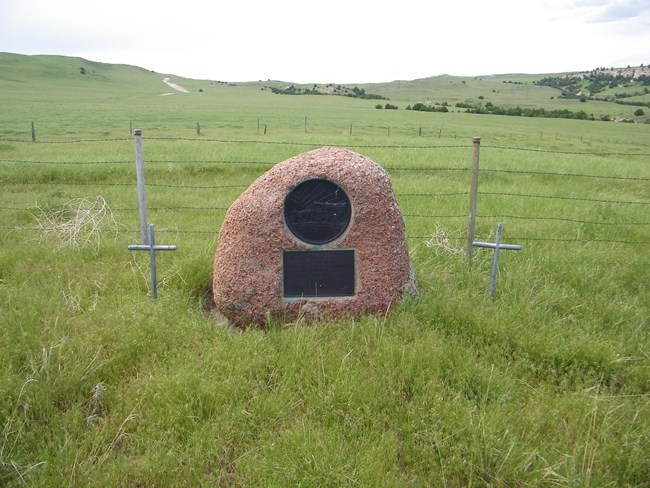 A granite boulder marks a grave with Christian crosses on each side.