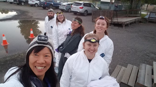 a team of 6 people outside wearing white coverall Tyvek suits to prevent cross contamination