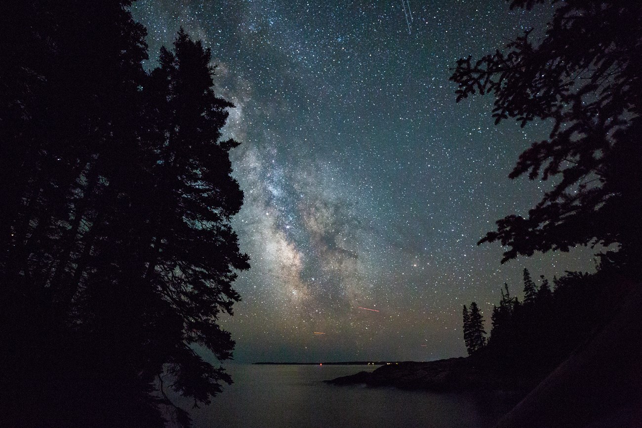 The night sky over Little Hunters Beach Night sky over a rocky beach and trees