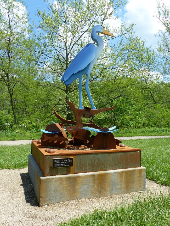 20200526 CRWT-SRBT heron statue A metal statue of a blue-and-white heron standing in water.