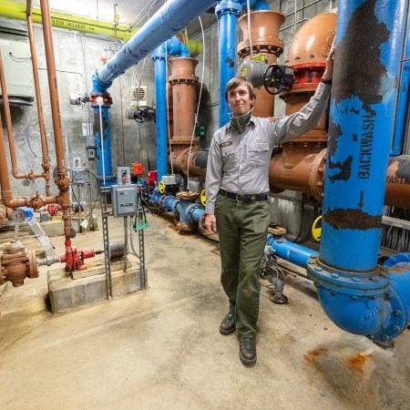 a park ranger standing in a room with a bunch of pipes