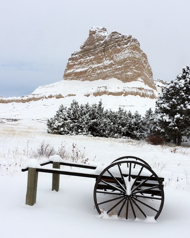 A replica Mormon handcart rests in the snow.