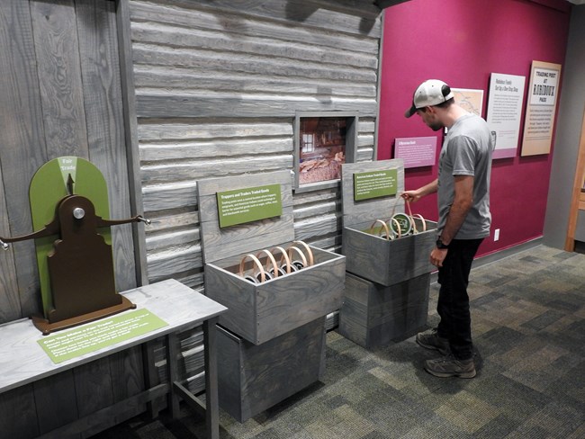 A visitor interacts with a tactile exhibit about trading posts.