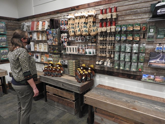 A woman peruses a variety of sales items displayed on shelves and pegs.