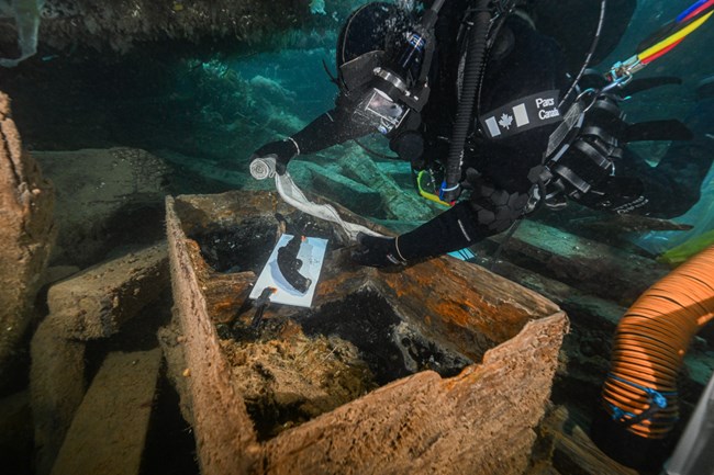 A Parcs Canada diver collects artifacts underwater.