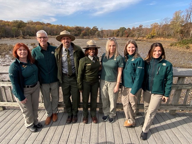 Members of the Canadian delegation stand with NPS rangers on a boardwalk.