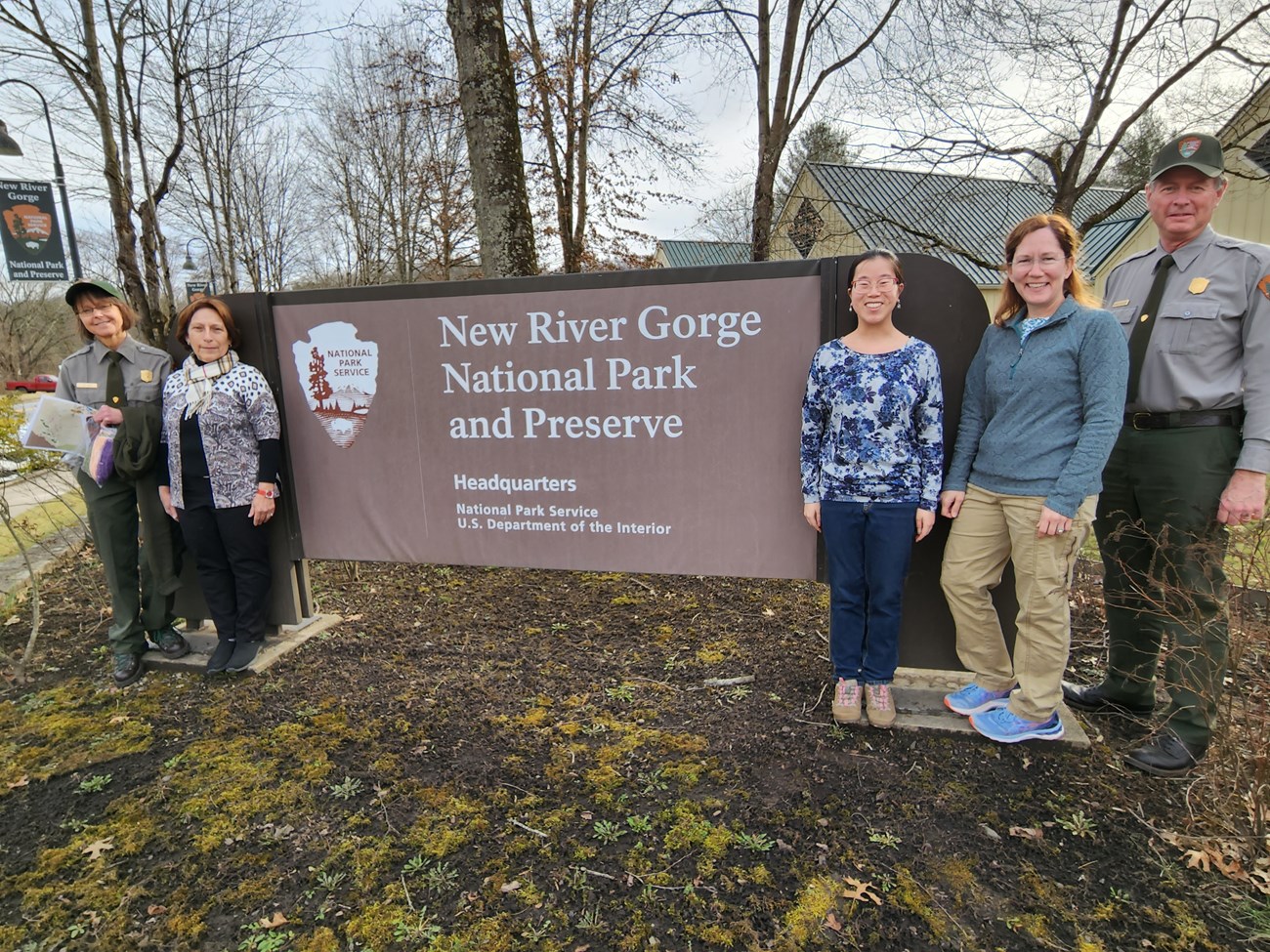 Group at New River Gorge National Park and Preserve Five NPS staff standing on either side (2 on the left, 3 on the right) of the New River Gorge National Park and Preserve sign that includes the text, "Headquarters, National Park Service, U.S. Department of the Interior" below it. The individual on the fa