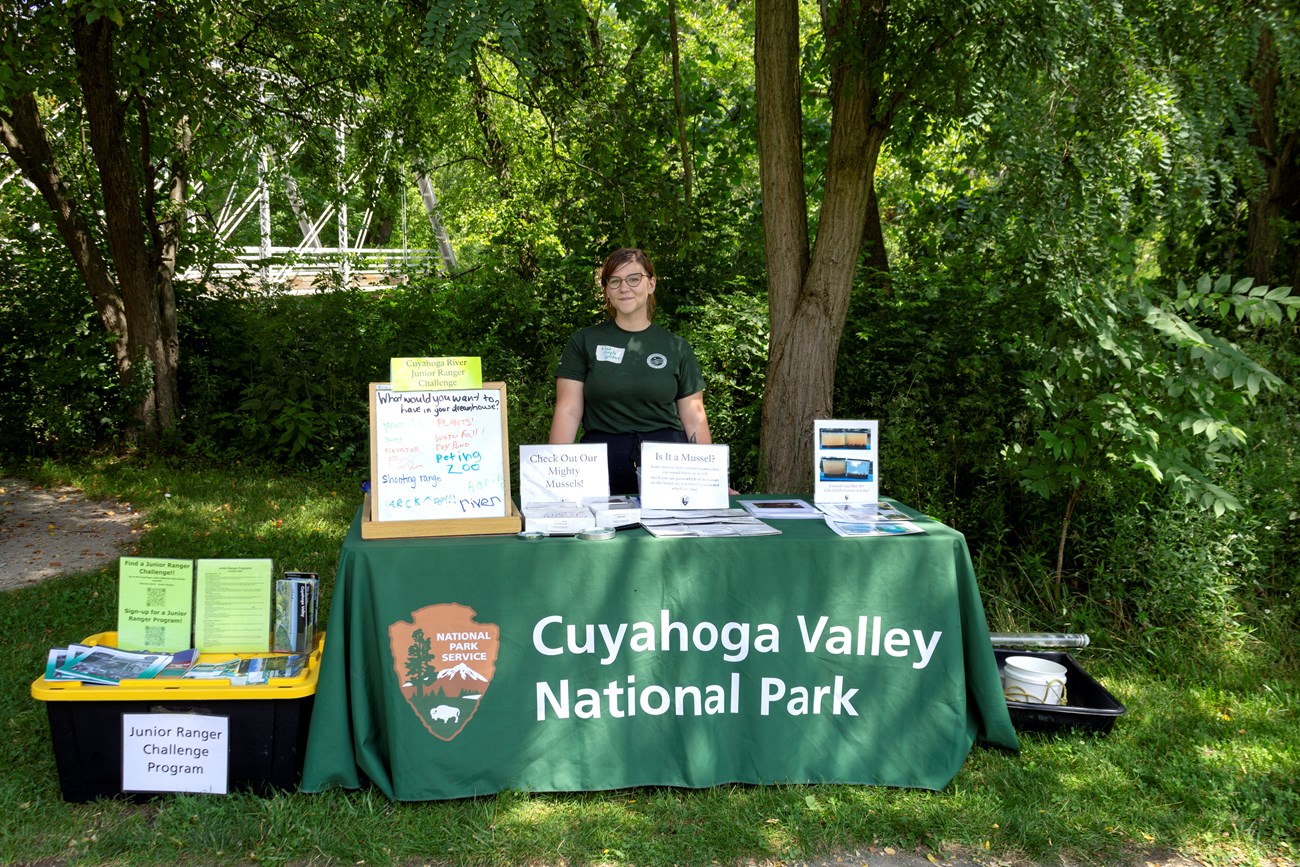 A woman stands behind a table with information.