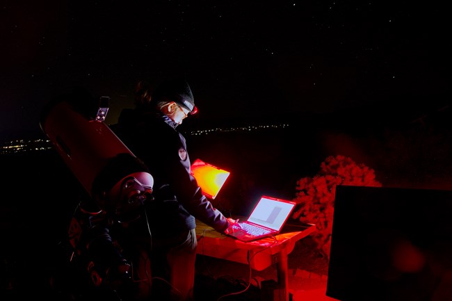 A person looking at a laptop at night.