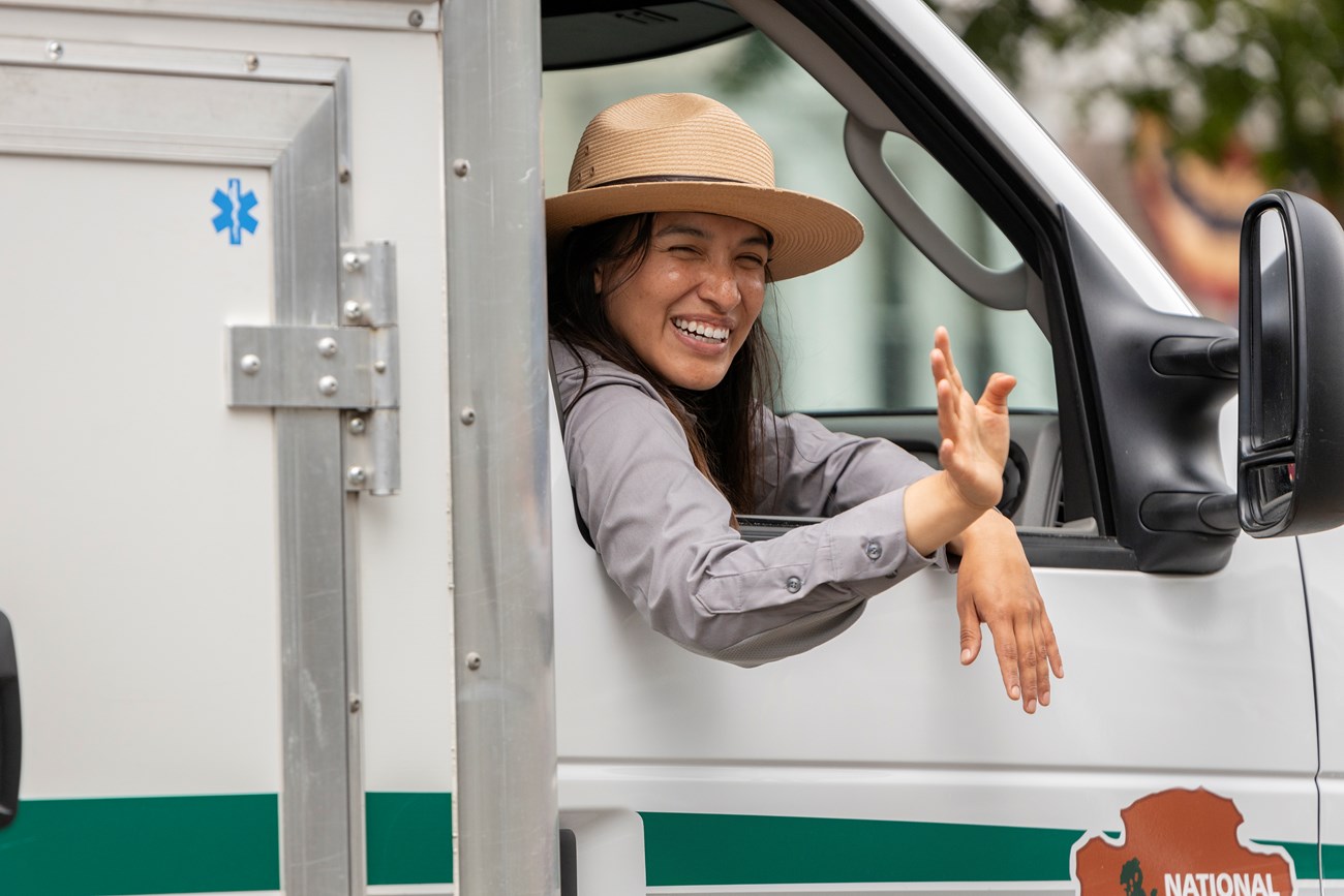 Jenn Vanegas-Gonzalez, General Ranger, waves while riding in the passenger seat of an ambulance. A park ranger waves to the public while riding in the passenger seat of an ambulance.