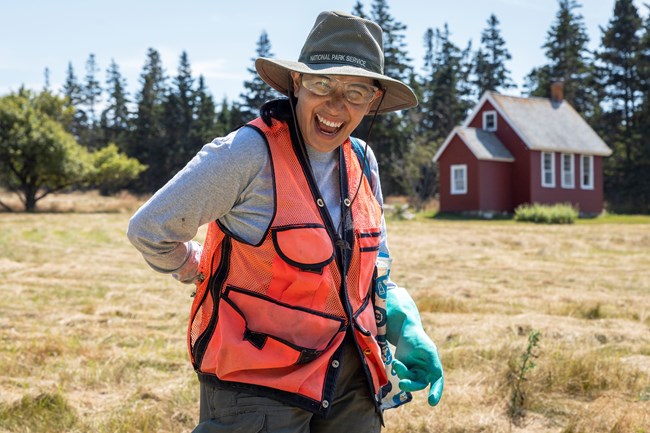 Jenn doing odd jobs while wearing a safety vest, safety googles, and large latex gloves.
