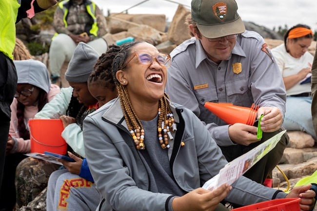Student laughing while conducting crab survey as they are being helped by a ranger.