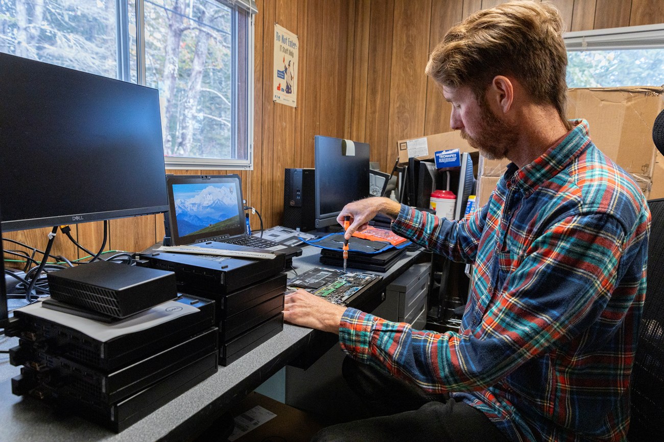 Sean works on replacing the battery of a government laptop. IT worker removes the battery on a laptop.