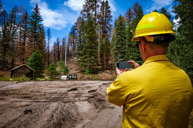 A man in a yellow hat and shirt stands in an empty parking lot