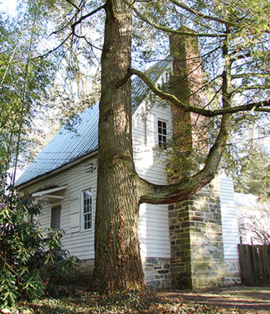 21 Swedish house image A white house with scalloped wood trim, a rock chimney and fenced yard area