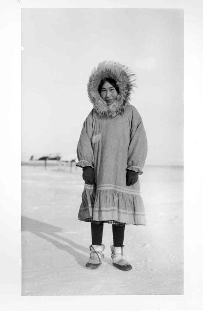 Louise Tunmaqq, an Inupiat woman, is dressed in a parka with a large fur ruff, gloves, and traditional fur boots. Louise Tunmaqq, an Inupiat woman, is dressed in a parka with a large fur ruff, gloves, and traditional fur boots.