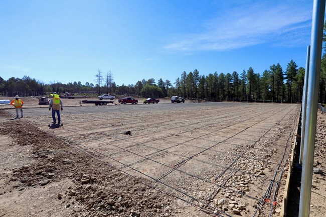 Two construction workers finish laying out reinforcement bar, or rebar, in preparation to pour a concrete base.