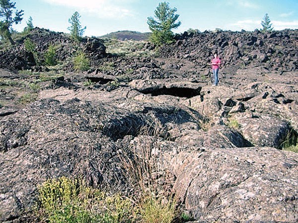 Photo of a person standing in a rugged volcanic landscape.