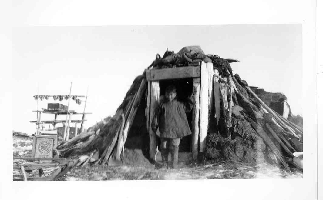 Boy in front of a sod house.