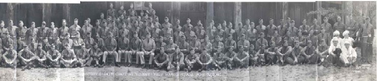 a group of nearly one hundred men in military uniforms sit and stand in three lines