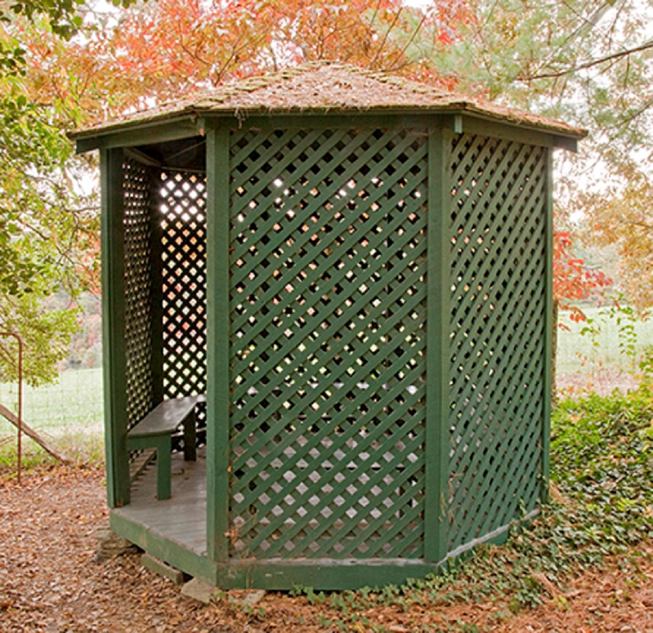 25 gazebo A small octagonal shaped building with green lattice and benches inside