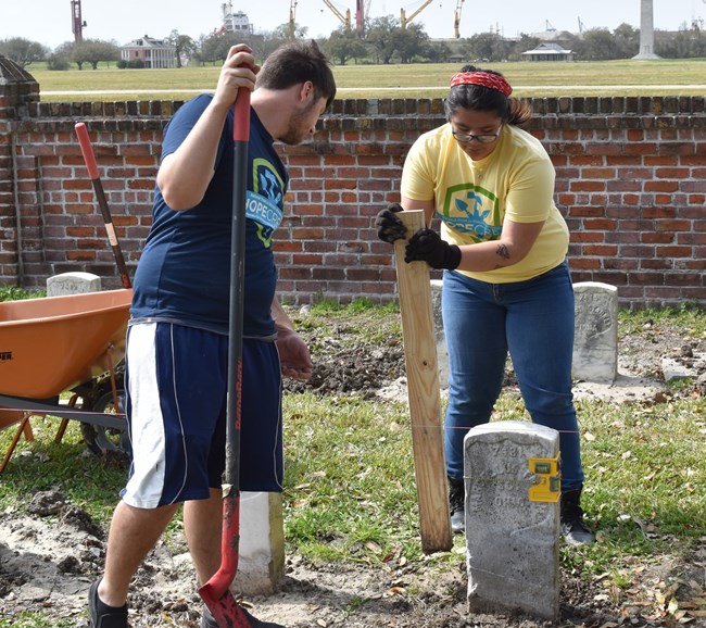 Kim Samaniego works with a HOPE Crew volunteer to reset a veteran’s grave marker at Chalmette National Cemetery.