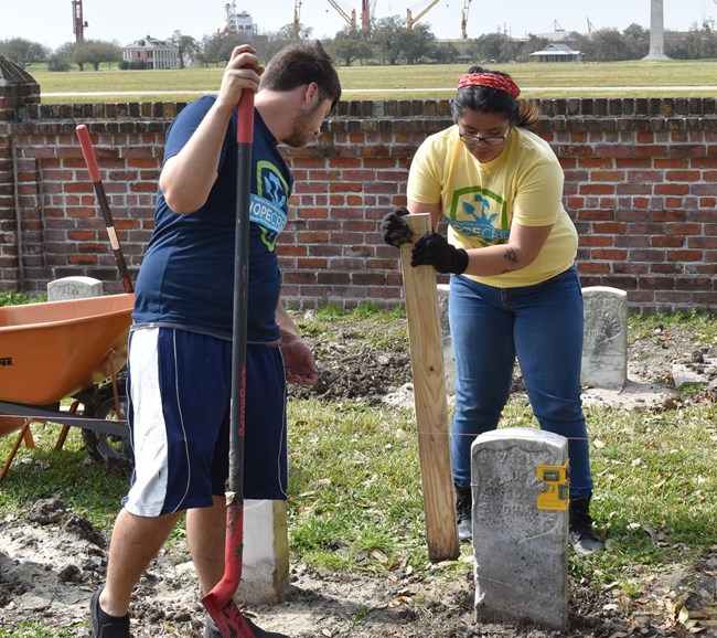 Kim Samaniego works with a HOPE Crew volunteer to reset a veteran’s grave marker at Chalmette National Cemetery. Kim Samaniego works with a HOPE Crew volunteer to reset a veteran’s grave marker at Chalmette National Cemetery.