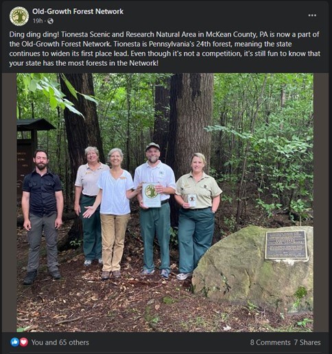25_TION-PA_OGFN Group of people standing by rock with plaque in forest