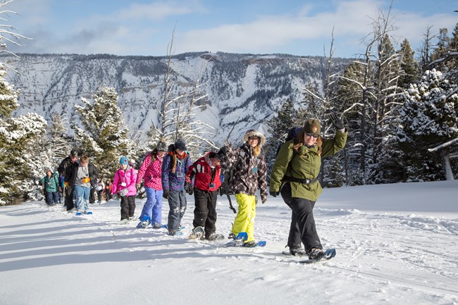 Make the Most of Your Trip a park ranger and kids snowshoeing up a slope