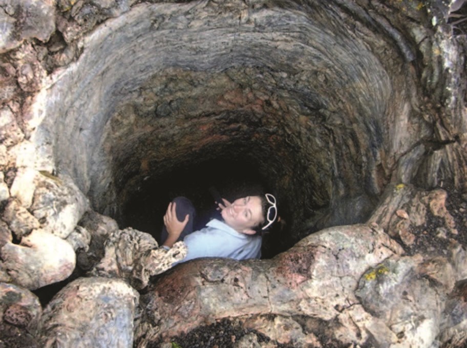 photo of a person in a round opening within lava rock