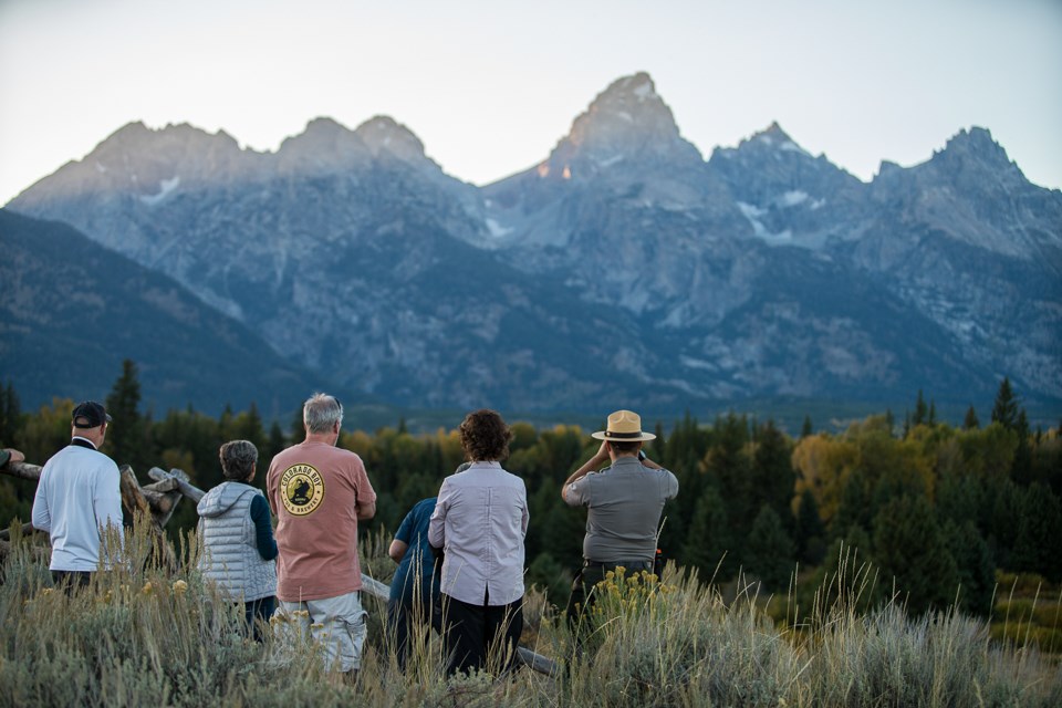 Grand Teton Ranger and visitors looking for wildlife with the Teton Range in the background