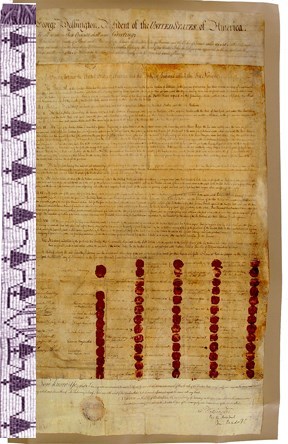 Faded parchment paper with red wax seals and delicate handwriting. A delicate beaded white and purple belt with an image of men holding hands.
