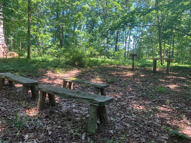 The Site of St. James Episcopal Church Today Three benches in a clearing in the woods in front of a podium and table.
