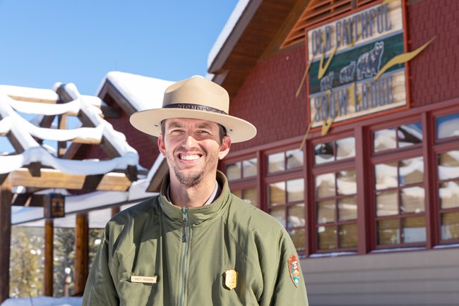 A park ranger smiles in front of the Old Faithful Snow Lodge.