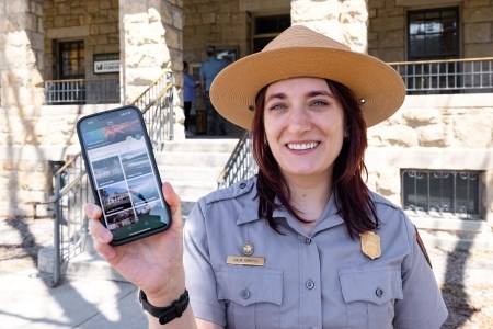 Expect Construction, Crowds, and Limited Connectivity a park ranger holding up a phone