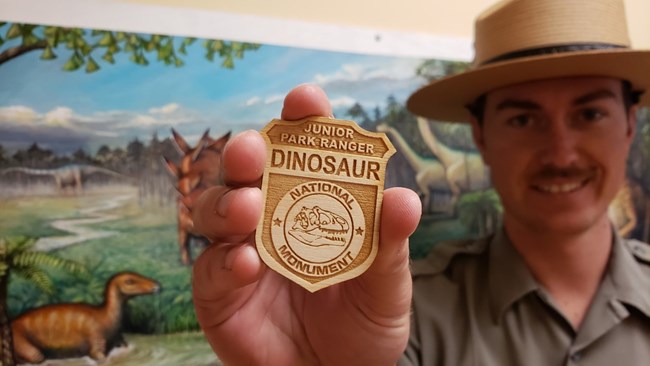 A ranger holds up a junior ranger badge