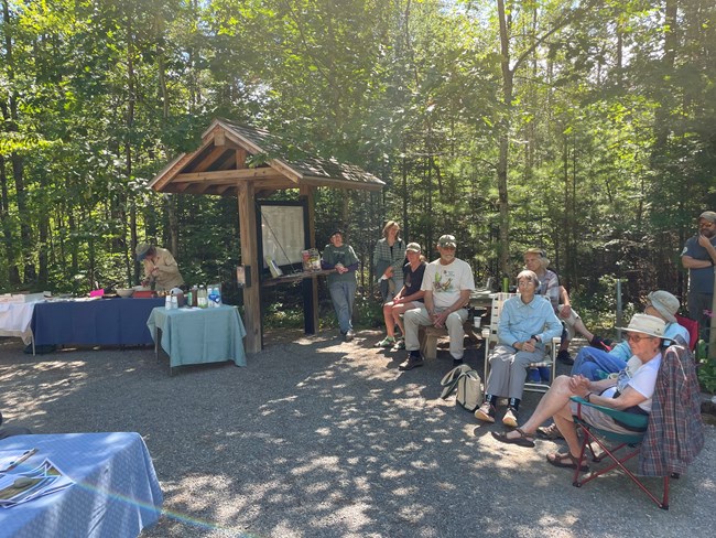 Group of people next to sign with forest in background