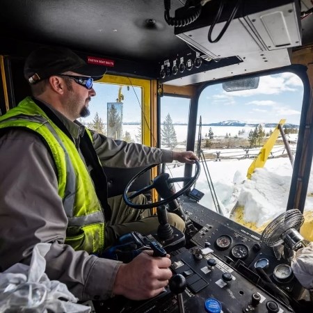 a park ranger operating a large snow plow