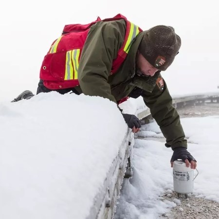 a park ranger adjusting a data collection tool in a thermal feature